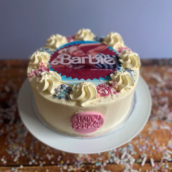 Barbie Buttercream Cake Barbie themed Buttercream birthday Cake with a Barbie picture featuring Margot Robbie, blue and pink sprinkles and a pink Happy Birthday Plaque